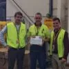 three men in the warehouse with certificate