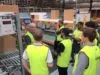 Various men in high-visibility vests at team meeting in warehouse