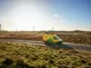 Yellow DHL truck driving through desert with windmills in the background