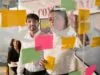 Team of three workers brainstorming with post-its on a glass wall