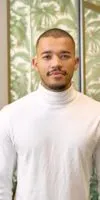 Portrait of a man working at DHL consulting with a white sweater looking directly at camera